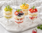 Three transparent dessert cups showcasing layered chocolate, mango, and berry parfaits with icons highlighting reusable, PS plastic, durable, and BPA-free features.